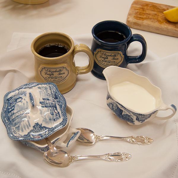 Coffee mugs with the Elizabeth Leigh Inn name, blue and white china and silver on a breakfast tray