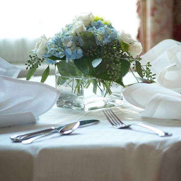 The dining room table set for breakfast with a hydrangea centerpiece