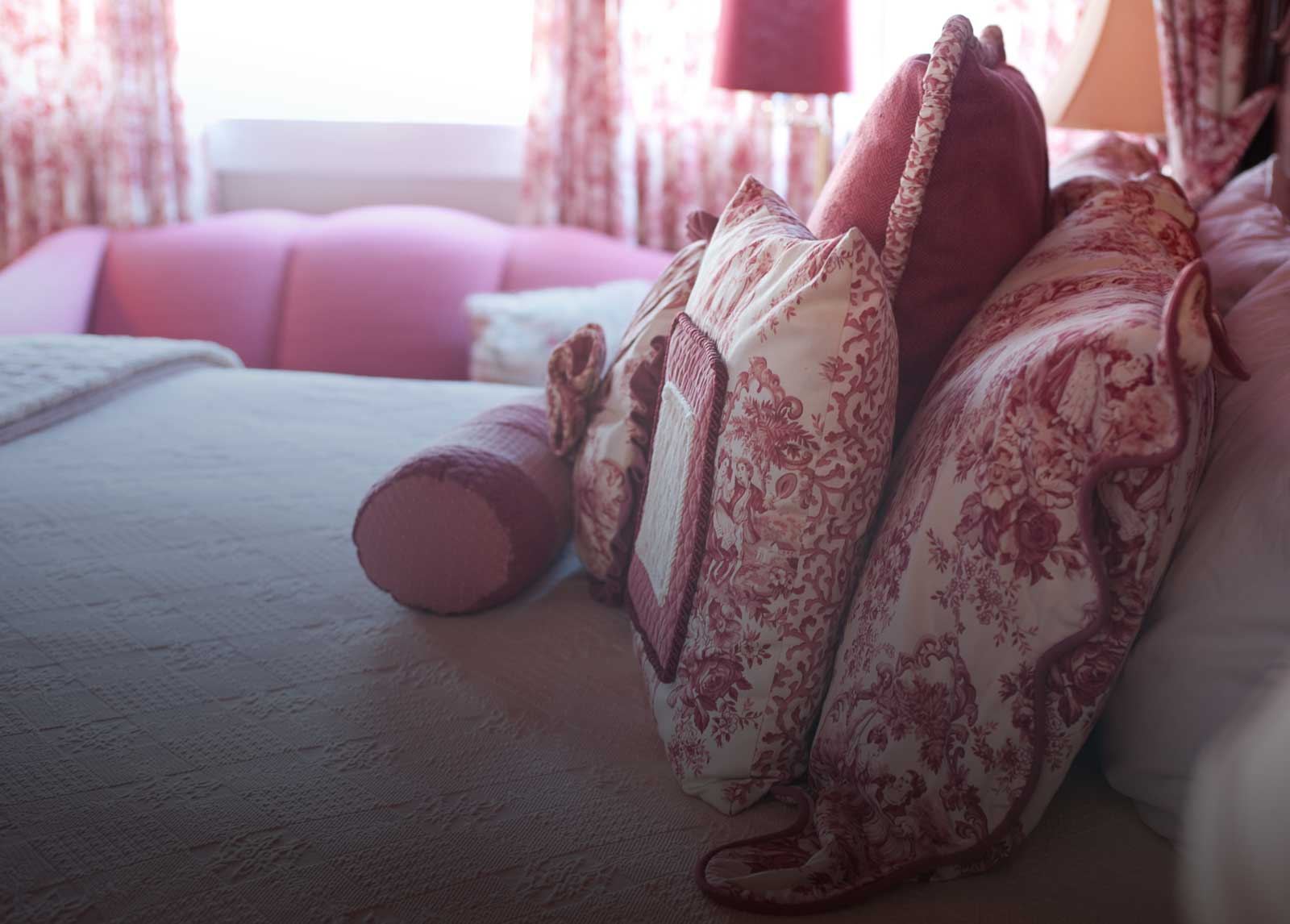 Close up of a bed dressed with rose toile pillows