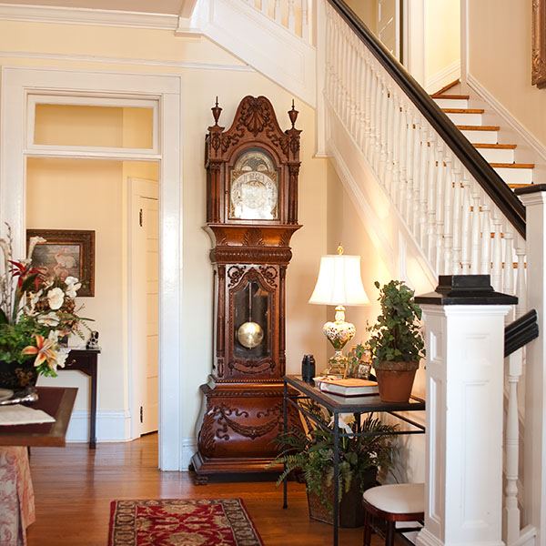 Entry hall of the inn with a grandfather clock and staircase