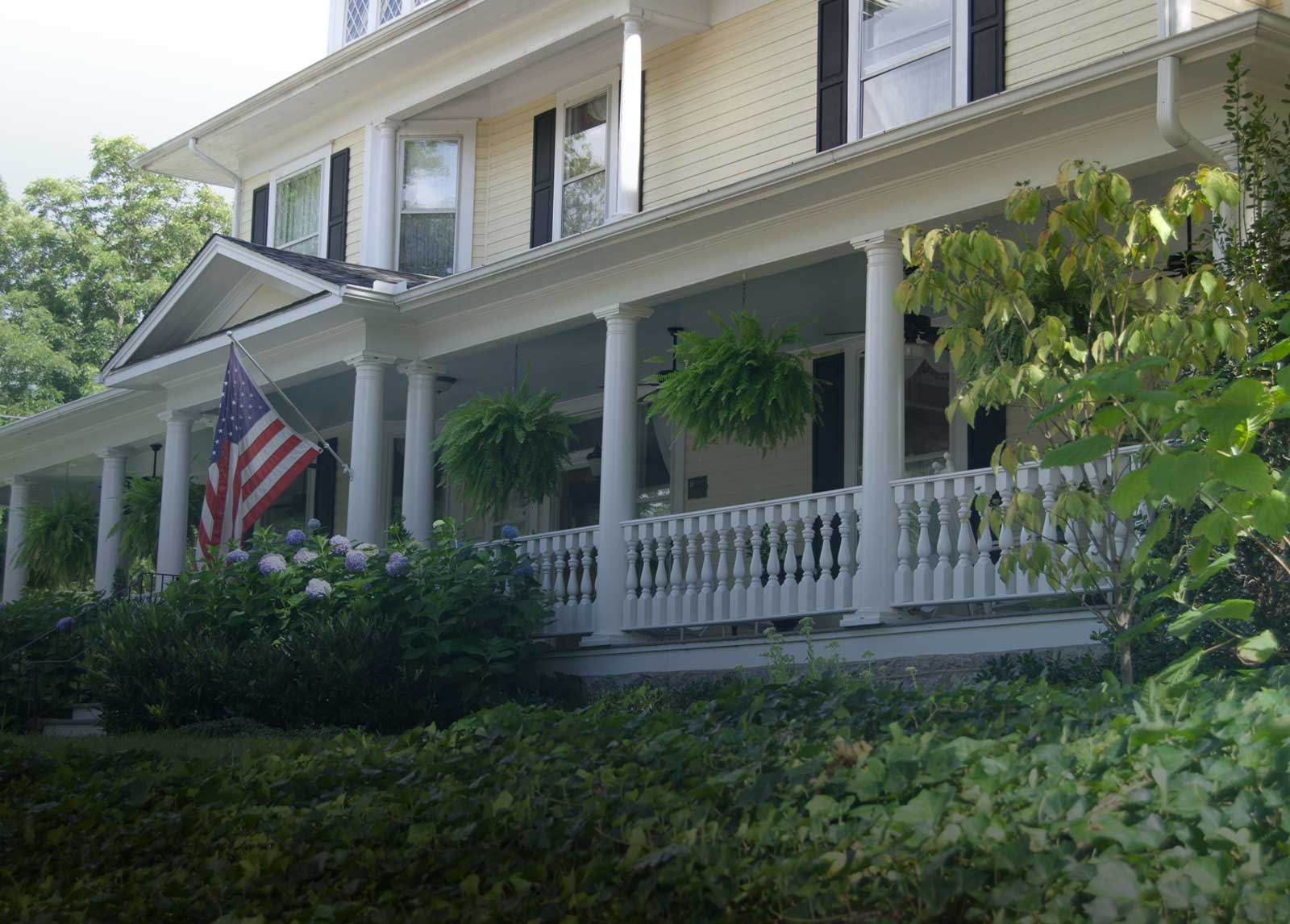Front porch of Elizabeth Leigh Inn, a yellow 1893 home with white columns and hydrangeas in Hendersonville, NC