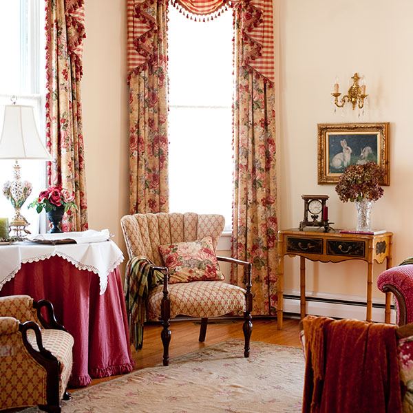 The parlor sitting room with armchairs, red drapes and a set table