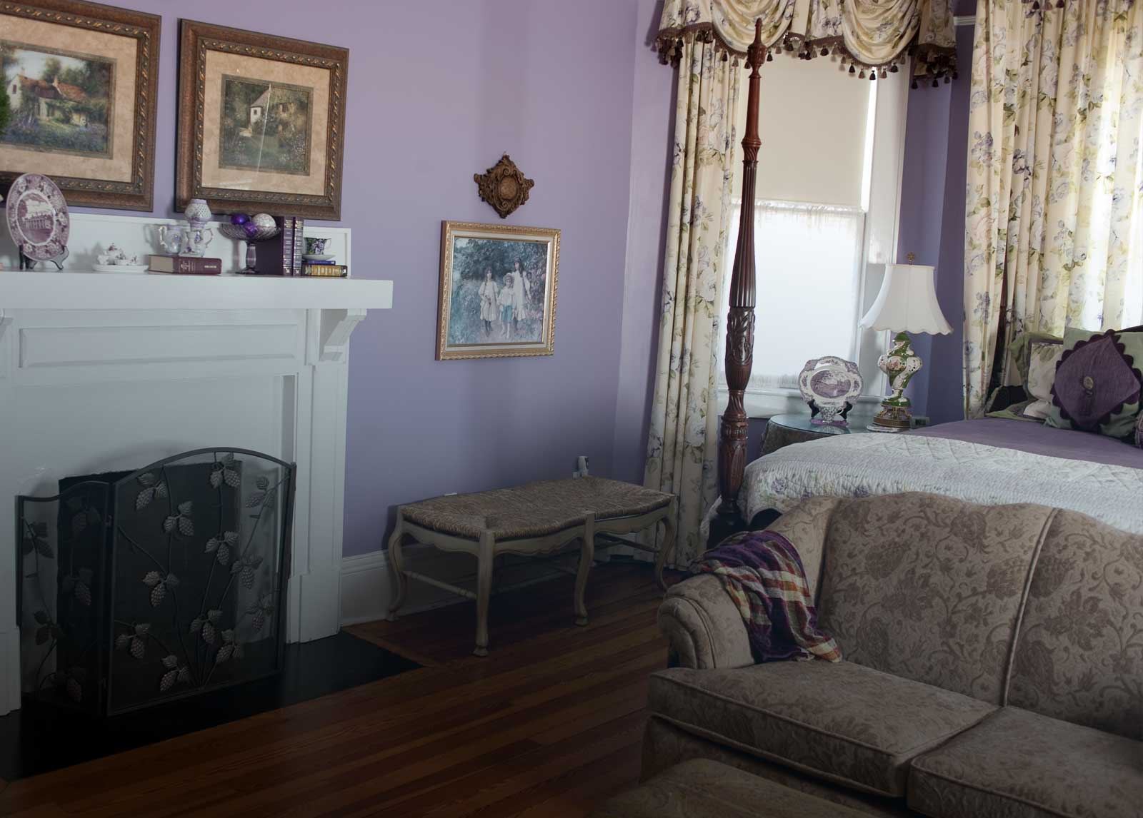 The Lavender Room, a four poster king bed in a lavender walled suite with a sofa and fireplace