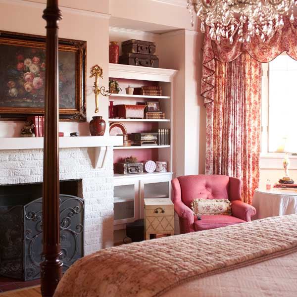 The Rose Room fireplace with bookshelves and a pink armchair
