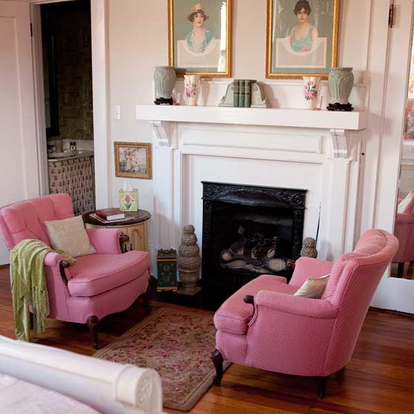 The Sage Room sitting area with a white fireplace and two pink armchairs